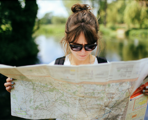 Woman outside wearing sunglasses and reading a map