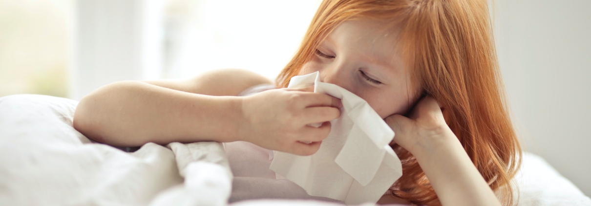 Girl sneezing into tissue