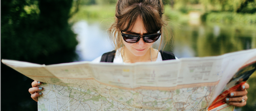 Woman outside wearing sunglasses and reading a map